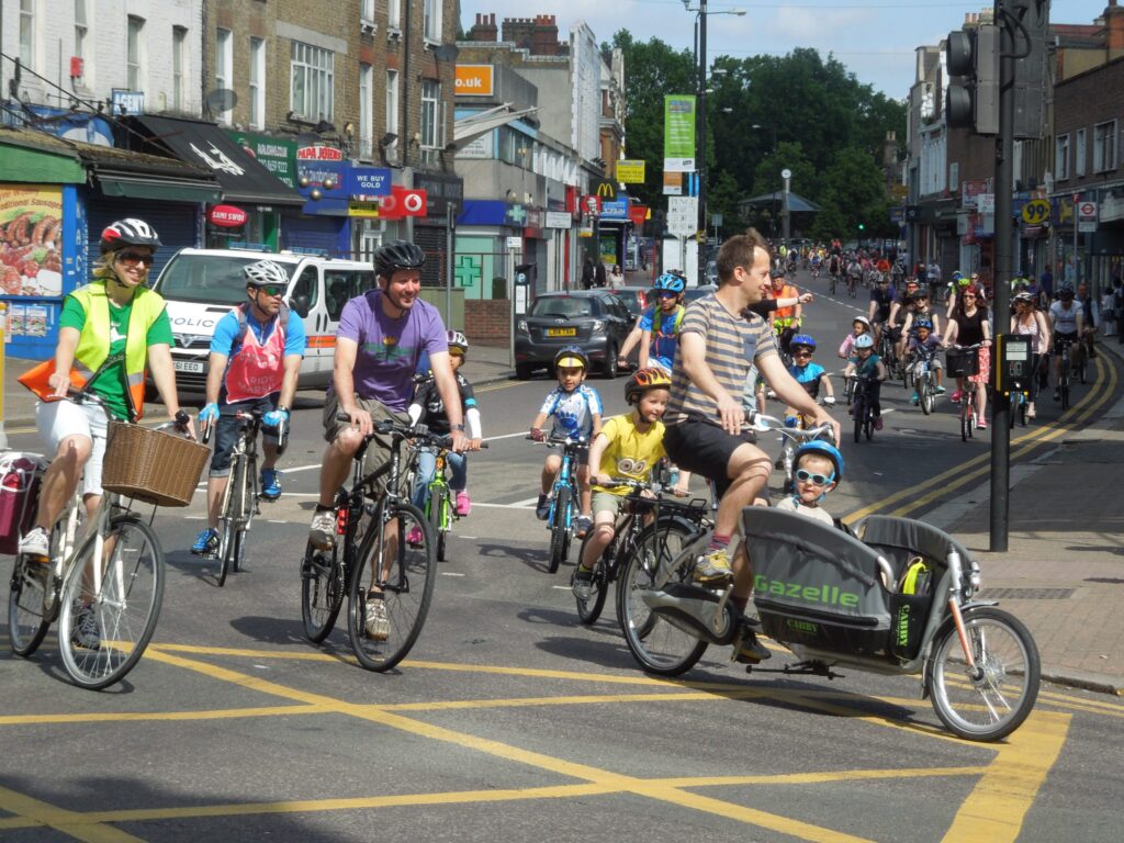A group of parents and children cycling on the road as part of the Tour de Penge cycle ride