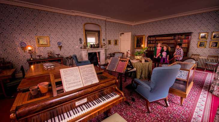 Interior of room inside Down House with piano, table and armchairs
